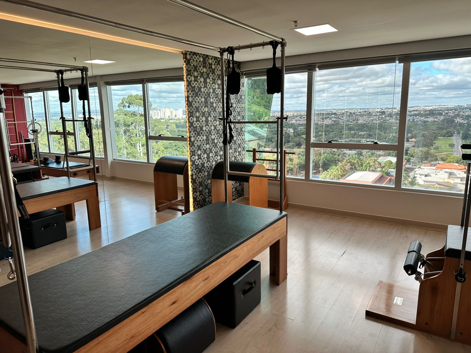 Estúdio de Pilates com equipamentos reformer e vista panorâmica de Brasília
